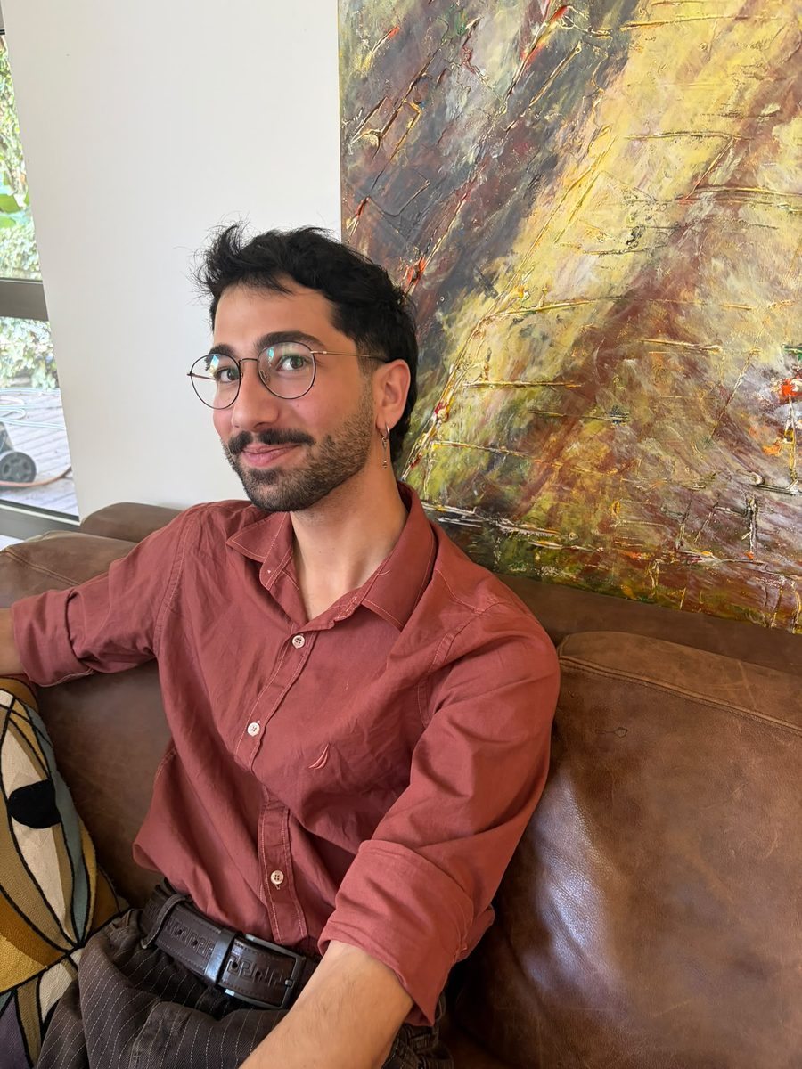 Noam Shaty on a leather sofa in front of an abstract painting
