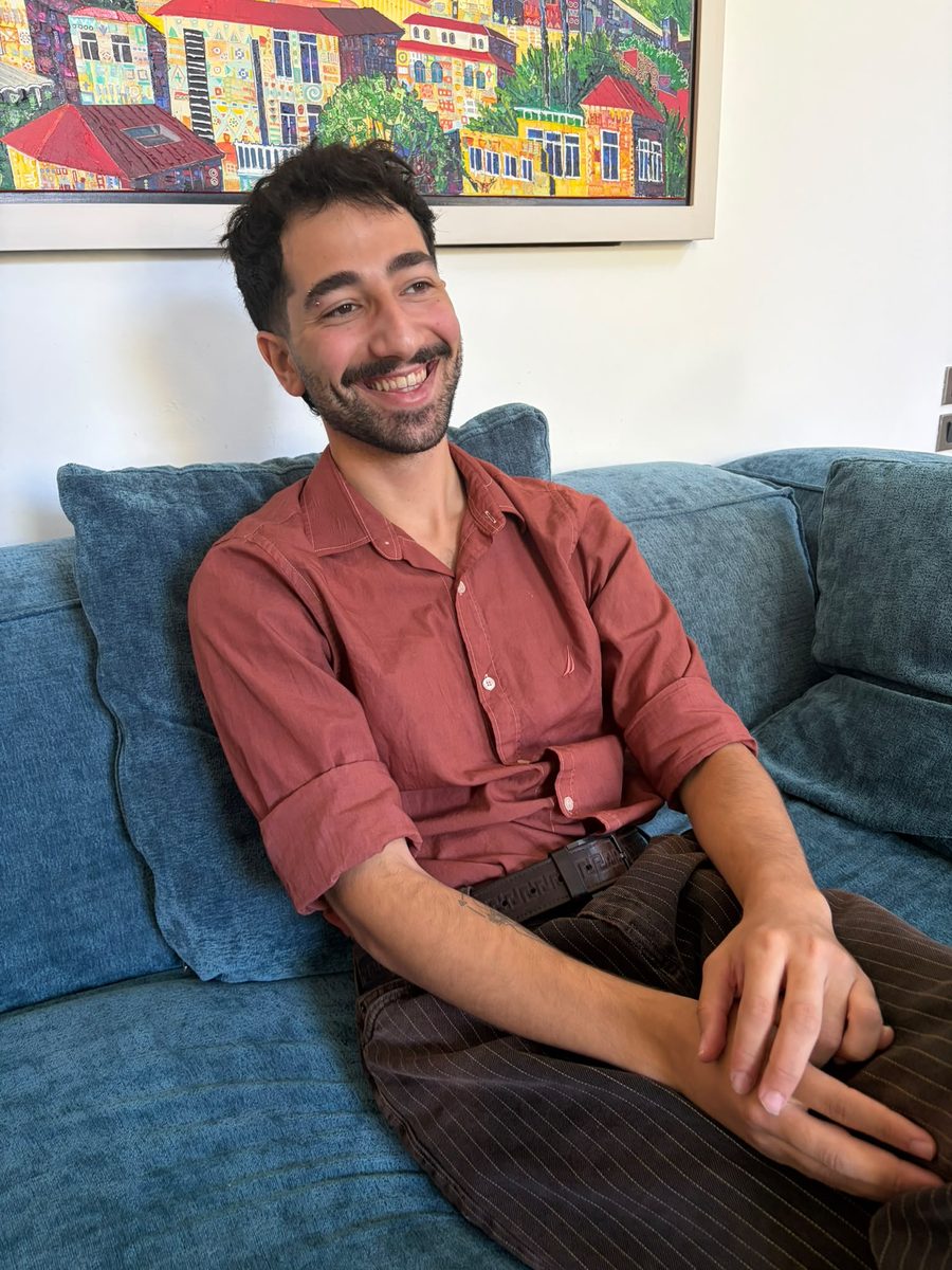 Noam Shaty laughing on a blue sofa